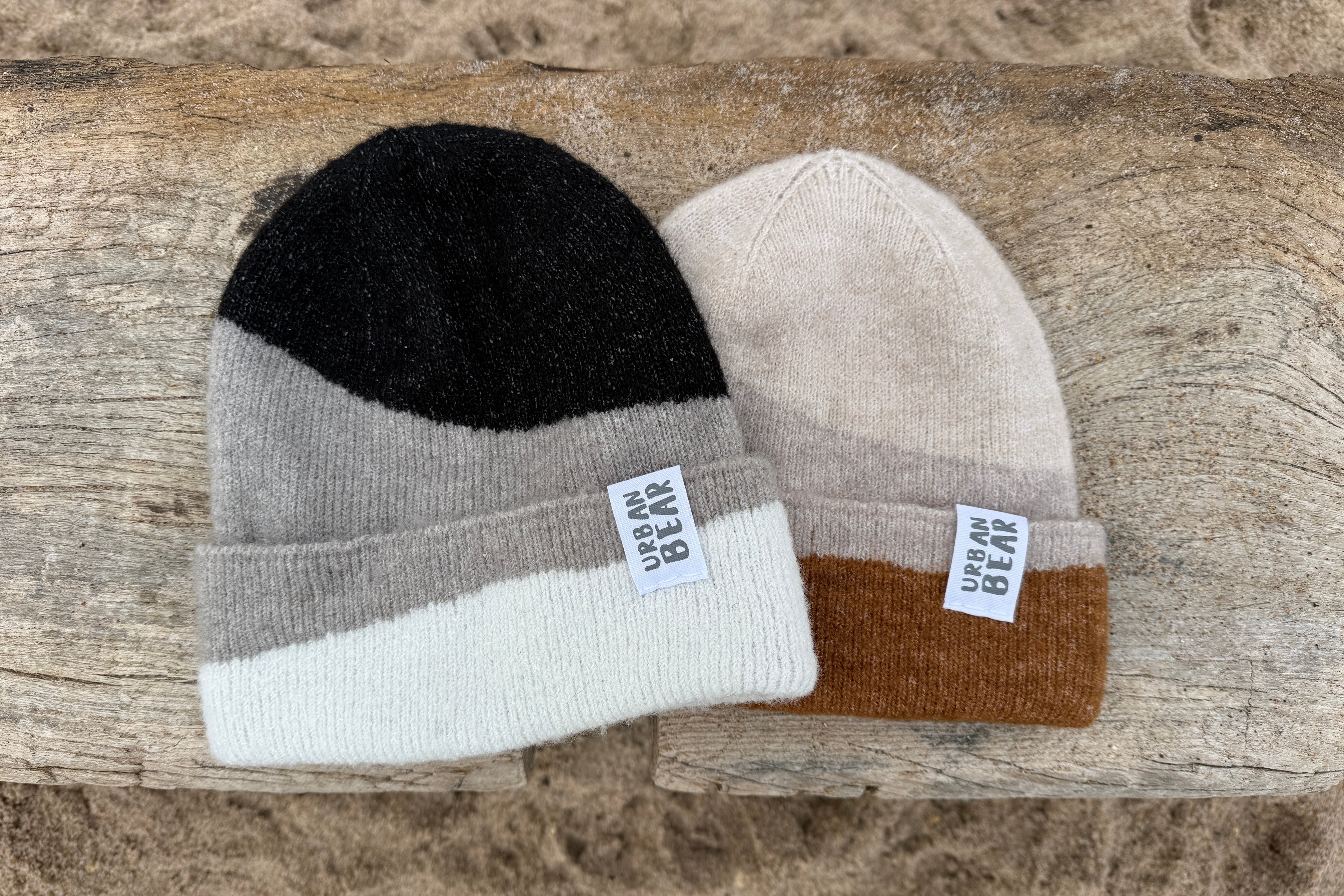 Two beanie hats with color-blocked design and brand labels on a wooden surface.