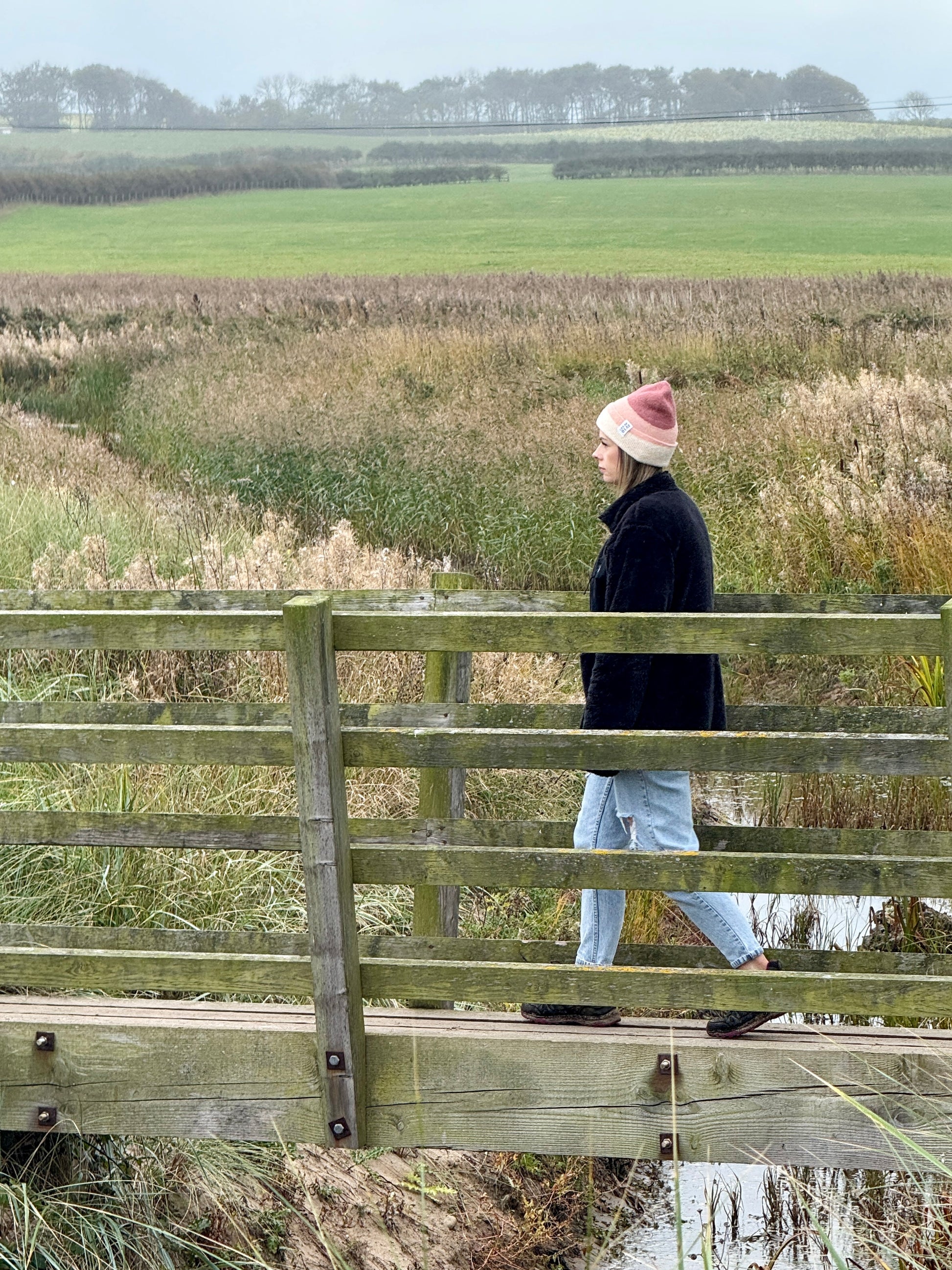 Person standing on a wooden bridge wearing a 3 tone beanie